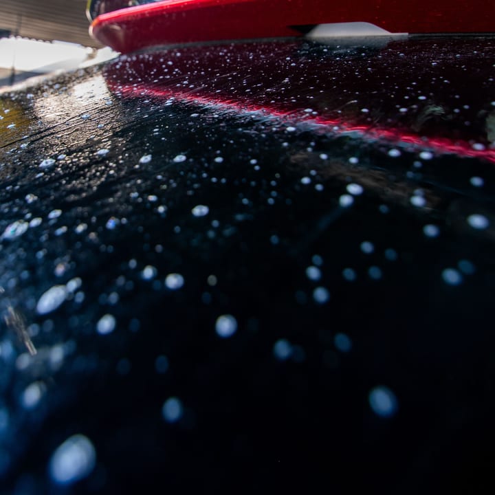 Gotas de agua sobre la carrocería negra de un coche